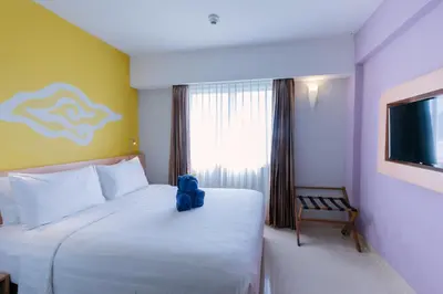 a bedroom with a large white bed and a window at Kuta Beach Hotel in Kuta