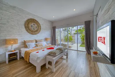 a bedroom with a large bed and a tv at Bali Cosy Villas Seminyak in Legian