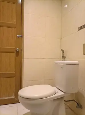a bathroom with a white toilet and a door at Sapta Petala Hotel in Kuta