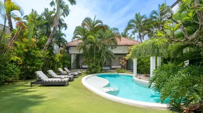 a swimming pool with lounge chairs and a house at Villa Alice by Villa Finder in Seminyak