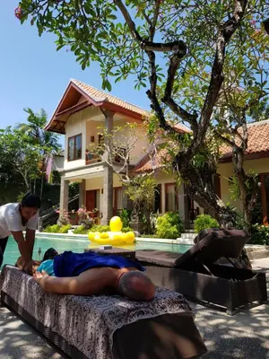 a man laying on a rock next to a swimming pool at Puri Mesari Hotel in Sanur
