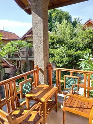 a wooden deck with a wooden table and chairs at Puri Mesari Hotel in Sanur
