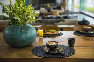 a table with a plate of food and a vase with flowers at Villa Keila Seminyak in Seminyak
