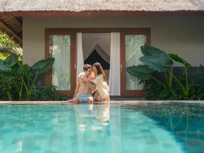 two women sitting on the edge of a swimming pool at The One Boutique Villa & Spa Seminyak in Seminyak