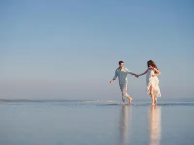 a man and a woman walking on the beach at The One Boutique Villa & Spa Seminyak in Seminyak