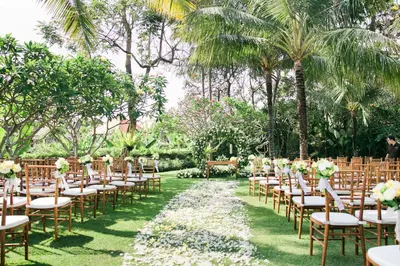 a row of tables and chairs in a garden at The One Boutique Villa & Spa Seminyak in Seminyak