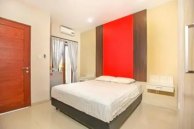 a bedroom with a bed with a red wall at KoolKost near Sunset Road Seminyak - Minimum Stay 30 Nights in Seminyak