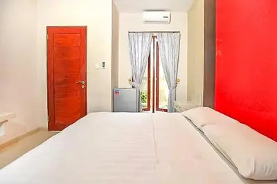 a bedroom with a large white bed with a red wall at KoolKost near Sunset Road Seminyak - Minimum Stay 30 Nights in Seminyak