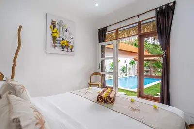 a bedroom with a bed with a view of a pool at Villa Jimmy in Seminyak