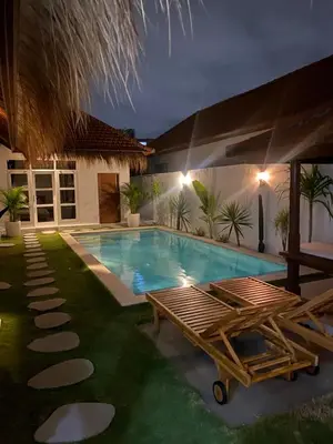 a swimming pool in a backyard at night at Villa Jimmy in Seminyak