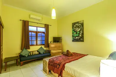 a bedroom with a bed and a chair and a window at Villa Mira in Seminyak