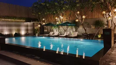 a swimming pool with chairs and umbrellas at night at The Banyumas Villa in Denpasar