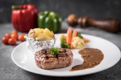 a plate of food with meat and vegetables on a table at The Banyumas Villa in Denpasar