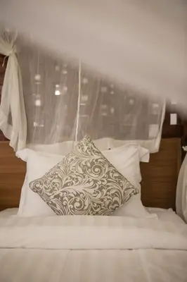a pillow sitting on top of a bed with white pillows at Sunset Paradise at Temple Hill Jimbaran in Jimbaran