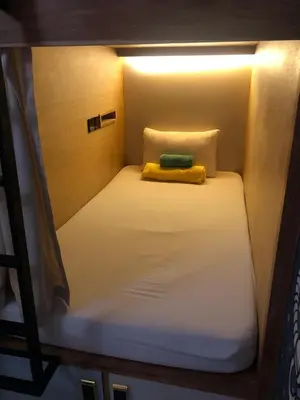 a small bed with a yellow blanket on top of it at Stellar Capsules in Seminyak