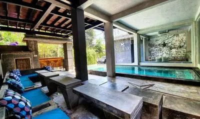 a house with a swimming pool with benches and a table at Stellar Capsules in Seminyak