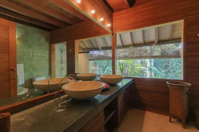 three sinks in a bathroom with wooden walls and a window at Villas Sin Sin in Canggu