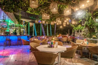 a restaurant with tables and chairs and lights at Bali Mystique Hotel & Apartment in Seminyak