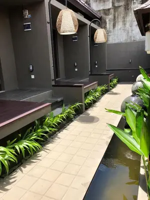a patio with benches and a pond with plants at Bali Elephants Boutique Villa in Jimbaran
