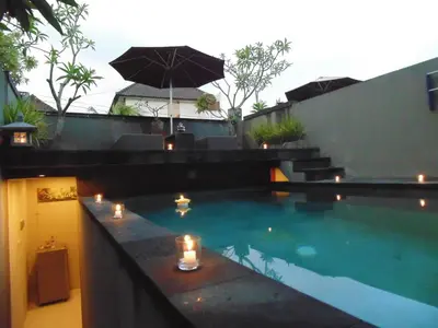 a swimming pool with candles and an umbrella at Bali Elephants Boutique Villa in Jimbaran
