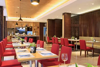 a dining room with tables and red chairs at Ohana Hotel Kuta in Kuta