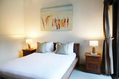 a bedroom with a bed with two lamps and a painting at Villa Marick in Seminyak