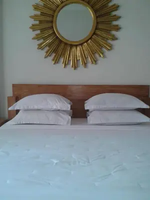 a mirror on the wall above a bed with pillows at Bali Court Hotel & Apartment in Legian
