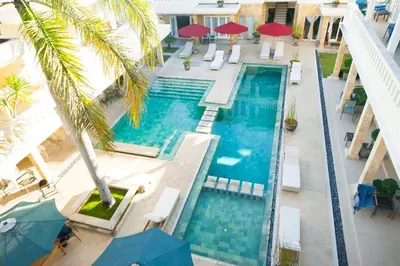 an overhead view of a swimming pool with palm trees and umbrellas at Bali Court Hotel & Apartment in Legian