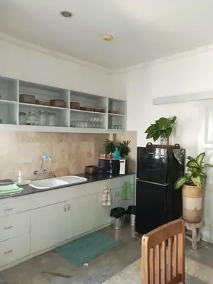 a kitchen with a black refrigerator and white cabinets at Bali Court Hotel & Apartment in Legian