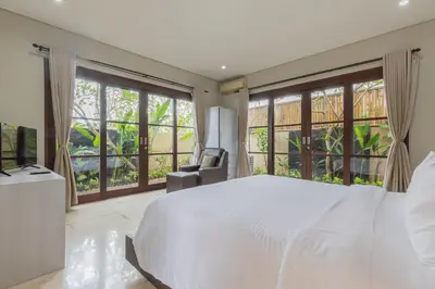 a bedroom with a white bed and large windows at Villa Harmony - Residence in Seminyak