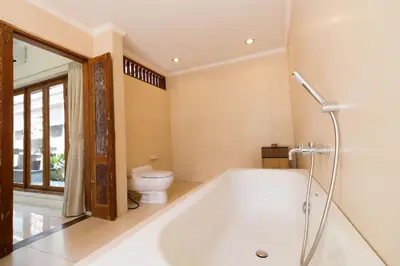 a bathroom with a tub and a toilet at Bali Royal Heritage Villas in Seminyak