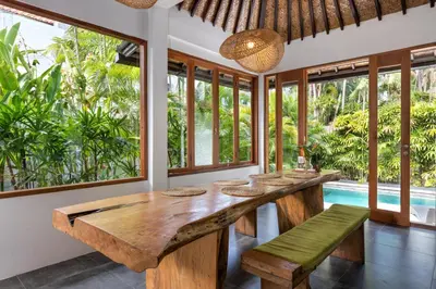 a dining room with a large wooden table and benches at Unicorn Shelter Villa in Seminyak