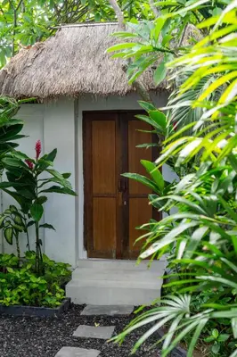 a small house with a thatch roof and a door at Unicorn Shelter Villa in Seminyak