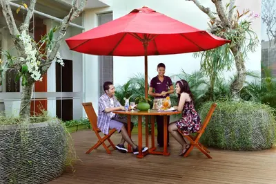 a group of people sitting at a table under an umbrella at Ibis Styles Bali Denpasar in Denpasar