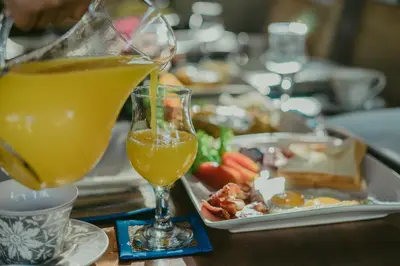 a table with a glass of orange juice and a tray of food at Villa Essence in Seminyak