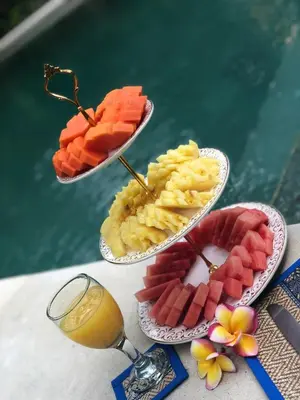 a table with two plates of food and a glass of orange juice at Villa Essence in Seminyak
