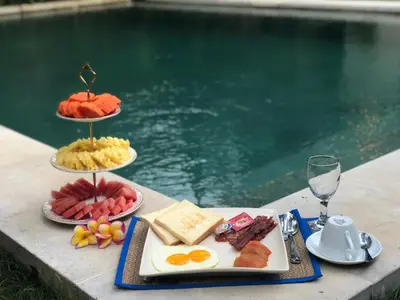 a table with three plates of food next to a pool at Villa Essence in Seminyak