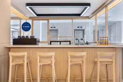 a bar with four stools at a counter in a restaurant at Holiday Inn Express Bali Sunset Road by IHG in Kuta