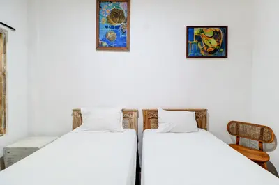 two beds in a room with paintings on the wall at Collection O Sanur Near Bali Exotic Marine Park in Sanur