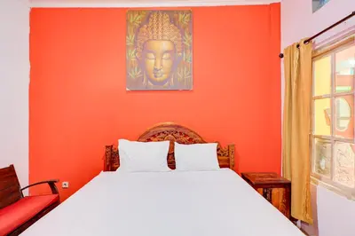 a bedroom with a bed with an orange wall at Collection O Sanur Near Bali Exotic Marine Park in Sanur