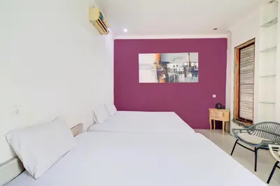 a bedroom with a white bed and a purple wall at Collection O Sanur Near Bali Exotic Marine Park in Sanur