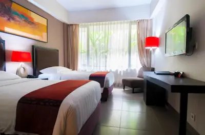 a hotel room with two beds and a flat screen tv at 100 Sunset Kuta Hotel & Ballroom in Kuta