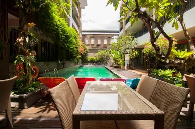 a patio with a table and chairs and a swimming pool at 100 Sunset Kuta Hotel & Ballroom in Kuta