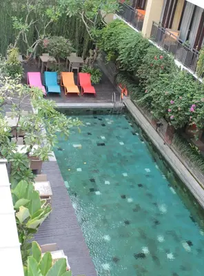 a pool of water with colorful chairs and plants at 100 Sunset Kuta Hotel & Ballroom in Kuta