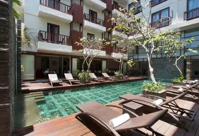 a hotel swimming pool with lounge chairs in a courtyard at d'primahotel Seminyak in Seminyak