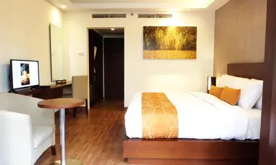a hotel room with a bed and a table and a painting at d'primahotel Seminyak in Seminyak