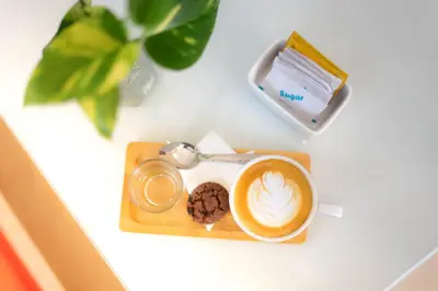 a cup of coffee and cookies on a table at Bali Summer Hotel by Amerta in Kuta