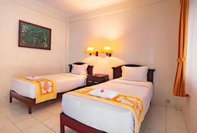 a hotel room with two beds and a window at Bali Summer Hotel by Amerta in Kuta
