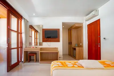 a bedroom with a bed and a desk and a television at Bali Summer Hotel by Amerta in Kuta