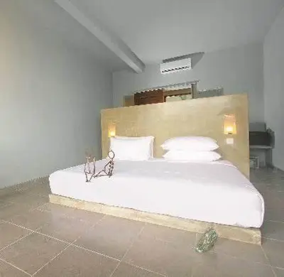 a bedroom with a large bed with white sheets and pillows at The Grey Boutique Inn in Legian